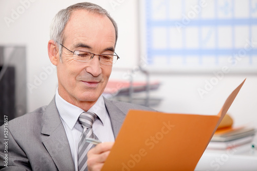 Photo: Older businessman writing in a file Older businessman writing in a file