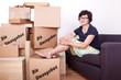 Foto: Woman sitting on the sofa in front of their moving boxes packed Woman sitting on the sofa in front of their moving boxes packed