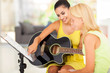 music teacher tutoring young girl to play guitar