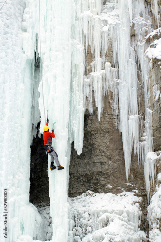 Photo: Ice climber struggles up a frozen waterfall. Ice climber struggles up a frozen waterfall.