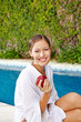 Photo: Junge Frau mit Apfel am Pool Junge Frau mit Apfel am Pool