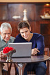 Senior und Mann schauen auf Laptop