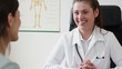 Young smiling doctor talking to her female patient at office