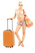 Full length portriat of a female tourist in bikini with a suitca