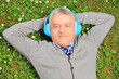 Photo: Mature man lying on grass with headphones, listening to music Mature man lying on grass with headphones, listening to music