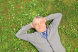 Foto: Senior man smiling and resting on grass in a park Senior man smiling and resting on grass in a park