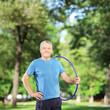 Foto: Smiling mature athlete with headphones holding a hulahoop in a p Smiling mature athlete with headphones holding a hulahoop in a p
