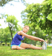 Photo : Young blond woman stretching in a park Young blond woman stretching in a park