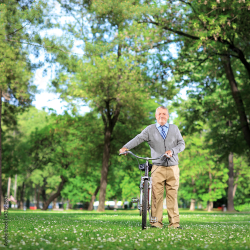 Photo: Mature man with a bicycle in a park Mature man with a bicycle in a park