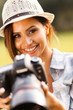 beautiful young woman holding camera outdoors