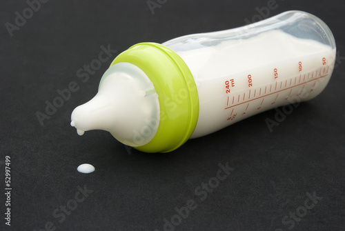 Photo: baby bottle with milk on black background baby bottle with milk on black background