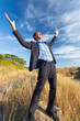 excited businessman on top of rock