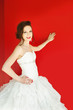 young bride leaning on red wall with copy space