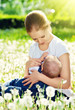 mother feeding her baby in nature green meadow with white flower