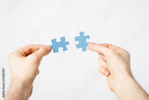 Photo: two hands trying to connect puzzle pieces two hands trying to connect puzzle pieces