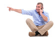 casual old man sits and points while on phone