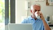 Serious man using his laptop while drinking a coffee