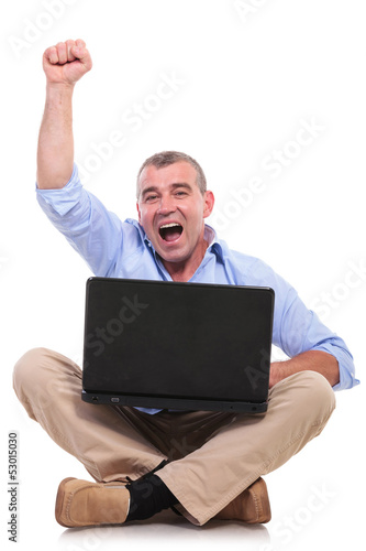 Photo: casual old man sits and cheers with laptop casual old man sits and cheers with laptop