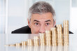 Mature Businessman With Stack Of Coins