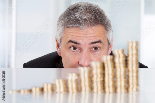 Photo: Mature Businessman With Stack Of Coins Mature Businessman With Stack Of Coins