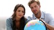 Couple looking at globe and picking travel destination