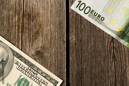 Photo: US and euro money over wooden background US and euro money over wooden background