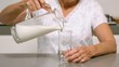 Woman pouring glass of milk in the kitchen