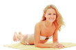 A  woman in a white swimsuit is lying on a yellow towel