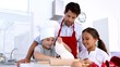 Father watching son roll pastry with sister