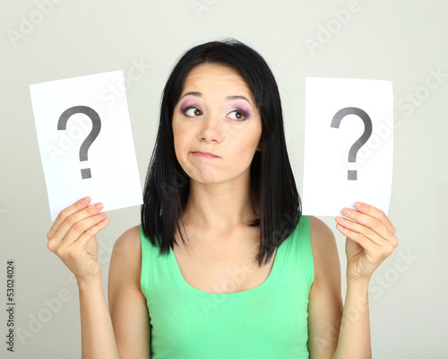 Photo: Woman with question marks on grey background Woman with question marks on grey background