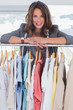 Photo: Smiling fashion designer leaning on clothes Smiling fashion designer leaning on clothes