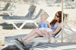 Young mother and her daughter sitting on a sunbed