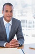 Cheerful businessman posing at his desk