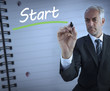 Businessman standing and writing the word start