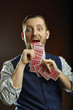 Joyful funny magician showing playing cards out of his mouth