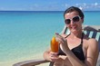 Beautiful young woman with a drink by the sea