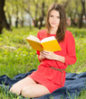 beautiful young girl reads book in park