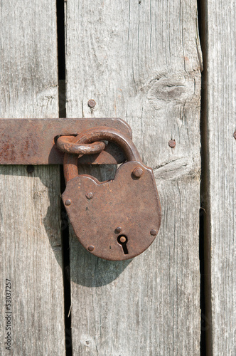 Photo: Old rusty padlock on a wooden door Old rusty padlock on a wooden door