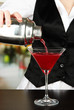 Barmen hand with shaker  pouring cocktail into glass,