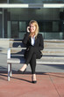 Businesswoman on the mobile phone sitting on a bench