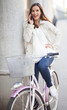 Happy young woman talking on the phone on her bike