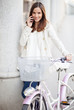 Young woman talking on the phone. Standing by her bike