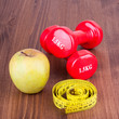 Red fitness sport dumbbells, apple, measure tape