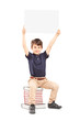 Photo: Happy school boy holding a blank panel above his head, seated on Happy school boy holding a blank panel above his head, seated on