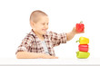 Photo: Little smiling boy holding colorful peppers on a table Little smiling boy holding colorful peppers on a table