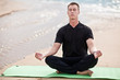 young man doing yoga on the beach