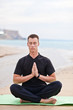 young man doing yoga on the beach