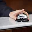 Weibliche Hand läutet Hotelglocke