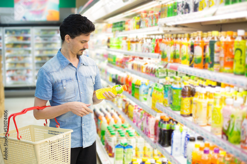 Photo: man in a supermarket buying a bottle of juice man in a supermarket buying a bottle of juice