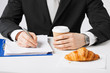 businessman with coffee writing something
